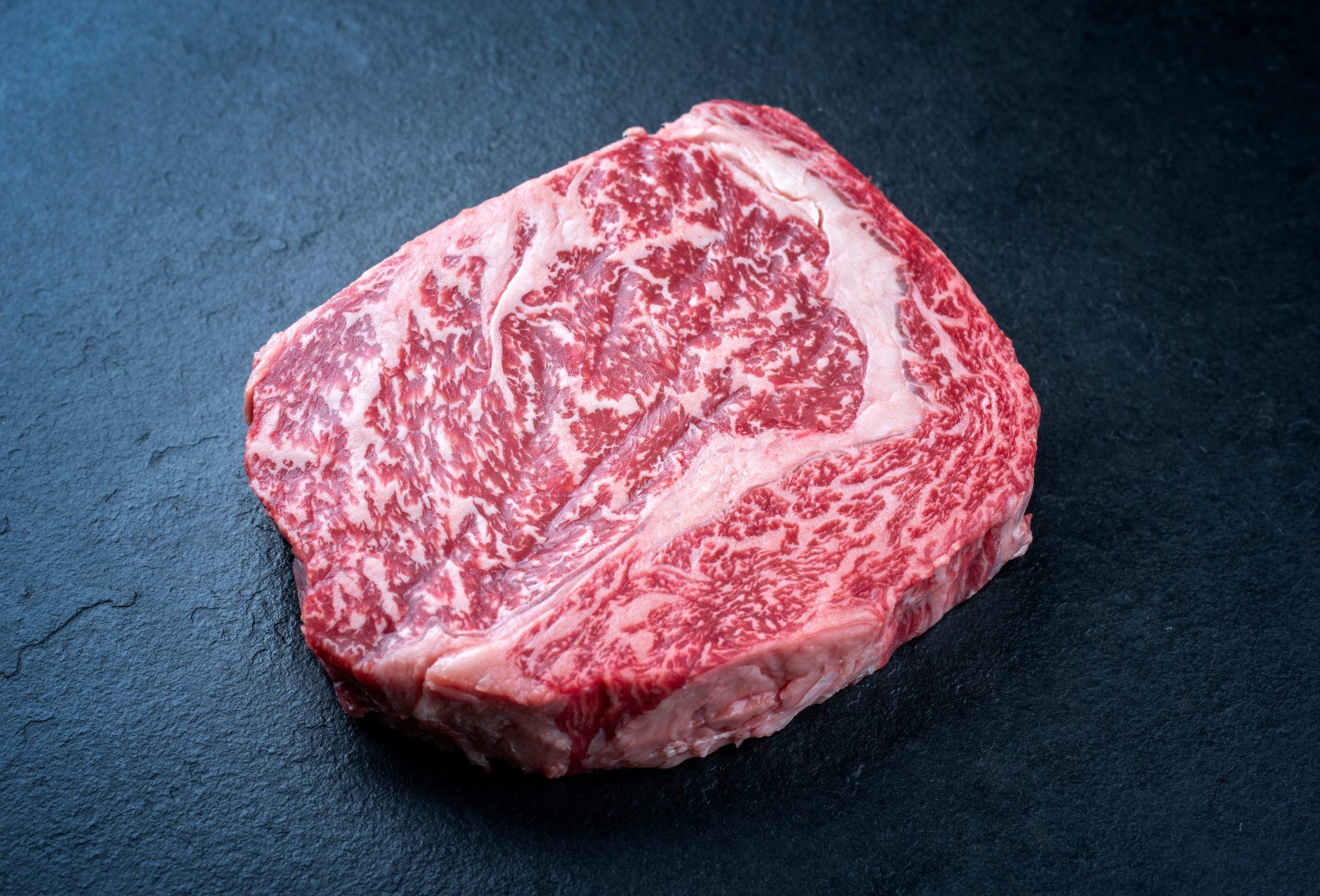 Raw dry aged wagyu cutlet steak cut offered as close-up on black background with copy space